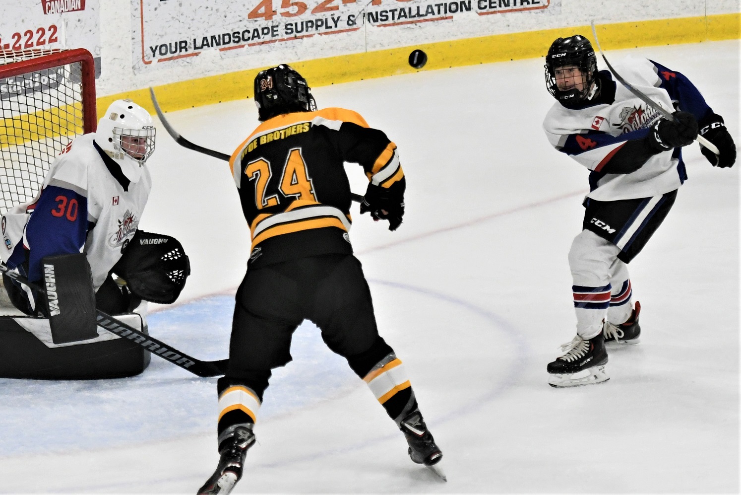 Dorchester Dolphin Nicholas Shearer (4) and Exeter Hawk Jaeden French (24) eye the puck in the air in front of Dolphins' goalie Jackson Mailloux, during PJHL action Sunday. Exeter won 4-2. <i> (photo / Rob J. Ross) </i> action